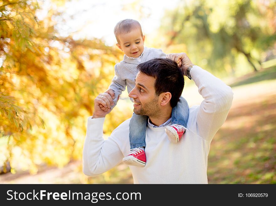 Young father and baby boy playing in autumn park at sunny day. Young father and baby boy playing in autumn park at sunny day