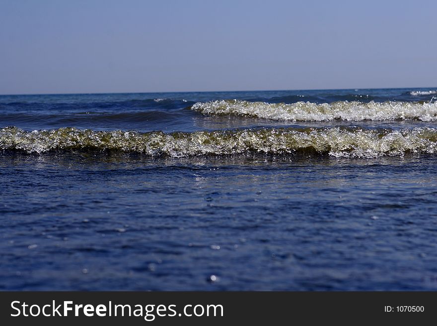 Miniature 2 inch waves crashing on a calm sea, with copy space. Miniature 2 inch waves crashing on a calm sea, with copy space