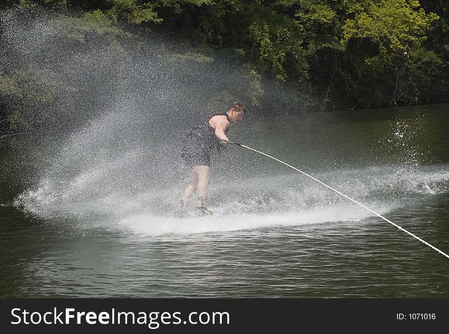Wakeboarder throwing up water beside boat