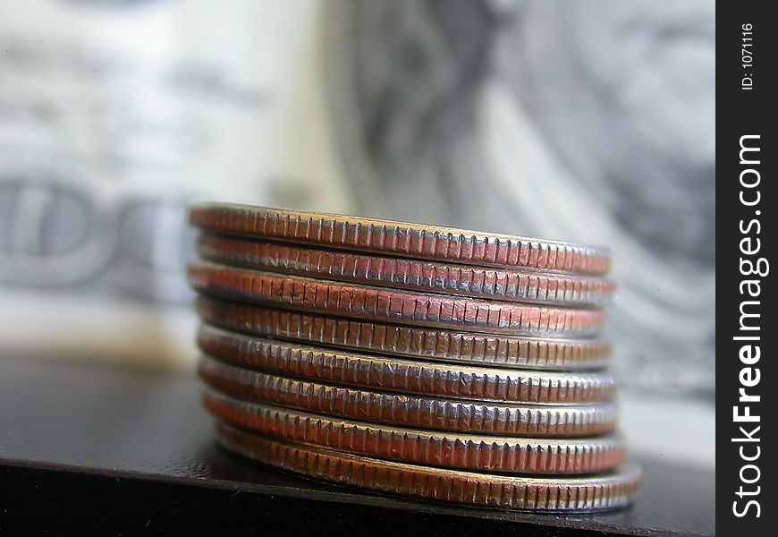 American Quarters stacked in the foreground with an American One Hundred Dollar Bill in the background. American Quarters stacked in the foreground with an American One Hundred Dollar Bill in the background