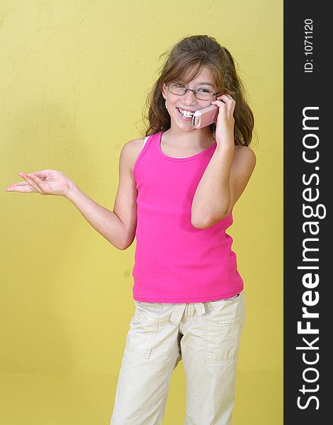 Pretty ten year old girl talking on the phone in a yellow room. Pretty ten year old girl talking on the phone in a yellow room.