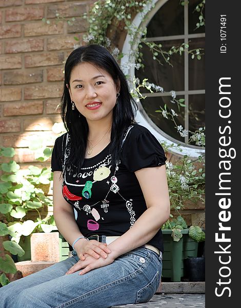 Portrait of a Korean woman sitting on steps in a garden