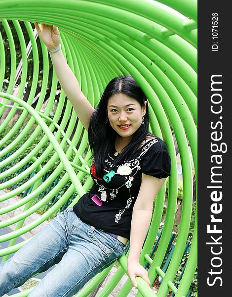 Asian woman playing in a green tunnel at the park. Asian woman playing in a green tunnel at the park