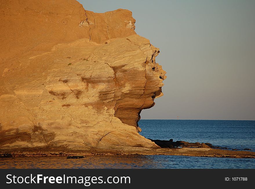 A cliff forming a face's profile of ochre stone. A cliff forming a face's profile of ochre stone