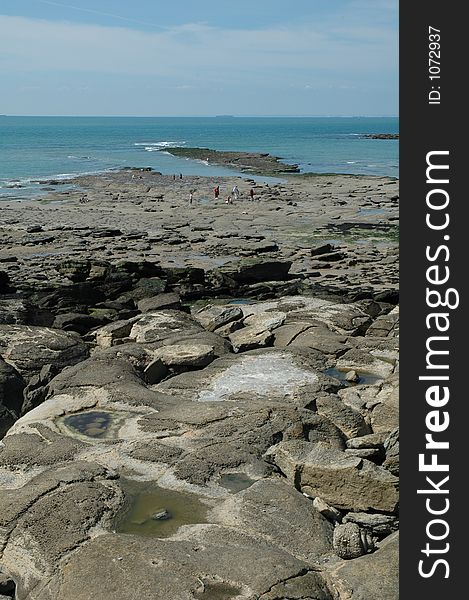 Walking on a rocky beach in France waiting for the ferry