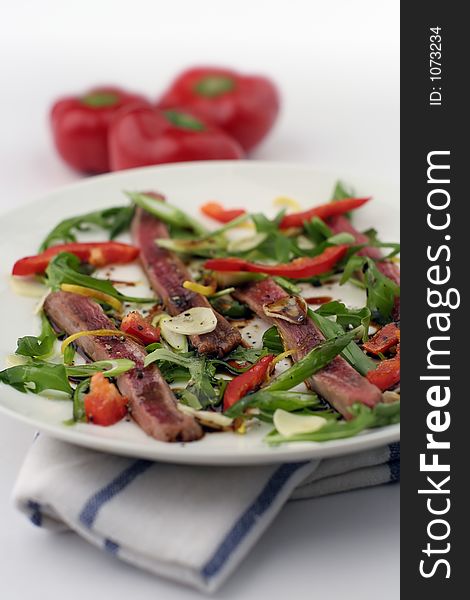 Finely sliced raw bleu beef with rocket and baby capsicum. Baby red capsicum or pepper. Reduced depth of field. Finely sliced raw bleu beef with rocket and baby capsicum. Baby red capsicum or pepper. Reduced depth of field.