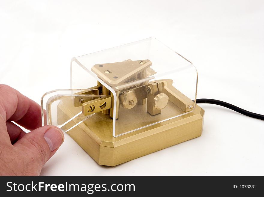 A morse code keyer. This brand is considered by many to be the finest available. With hand, on a white background.