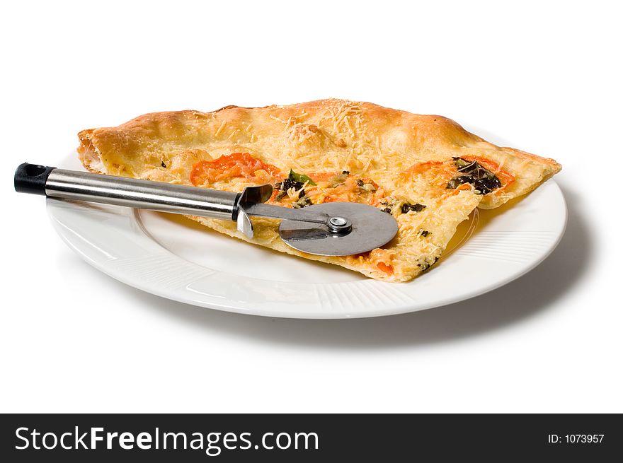 Slice of pizza on white plate with pizza cutter isolated on white.