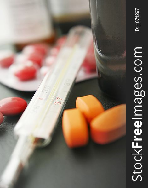 Thermometer with medication. Focus on thermometer. Thermometer with medication. Focus on thermometer