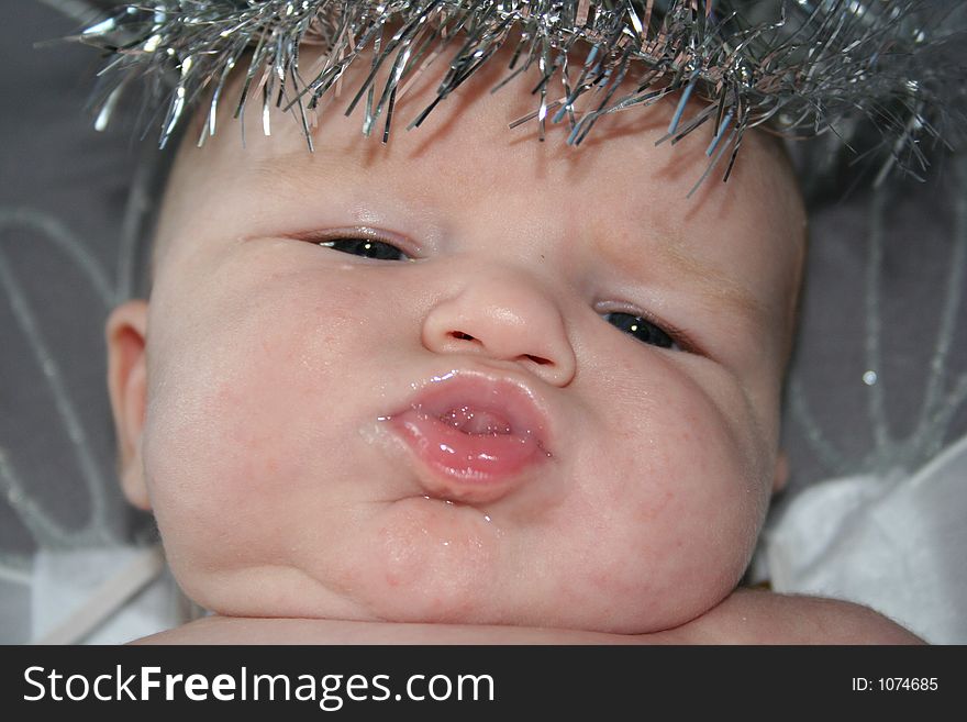 A close up of a chubby baby with a halo sticking it's tongue out. A close up of a chubby baby with a halo sticking it's tongue out.