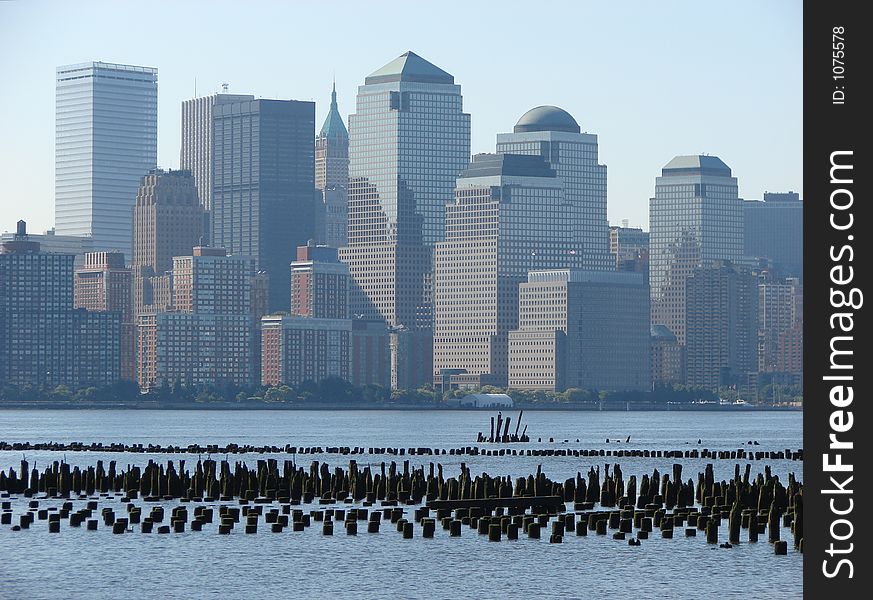 The skyline of New York City in the early morning haze. It is contrasted with the sharp and clear wood pilings in front of the city, in the Hudson River. The skyline of New York City in the early morning haze. It is contrasted with the sharp and clear wood pilings in front of the city, in the Hudson River.