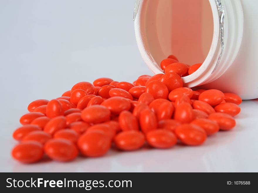 Orange pills poured out of bin isolated over white