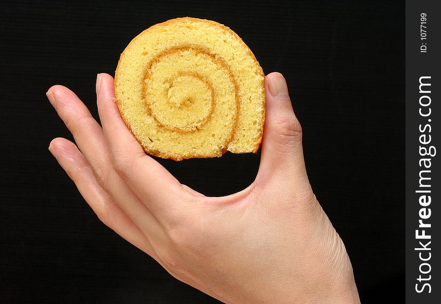 A slice of rolled cake is being held by hand. A slice of rolled cake is being held by hand