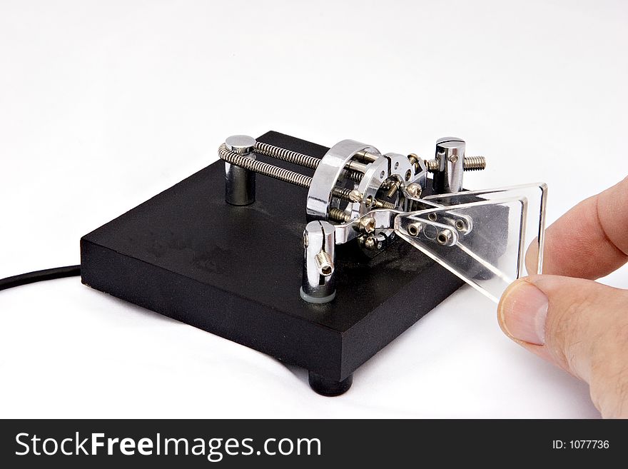 A black morse code squeeze keyer shown with a hand on a white background. A black morse code squeeze keyer shown with a hand on a white background.