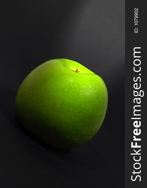 Green apple on black background with spotlight