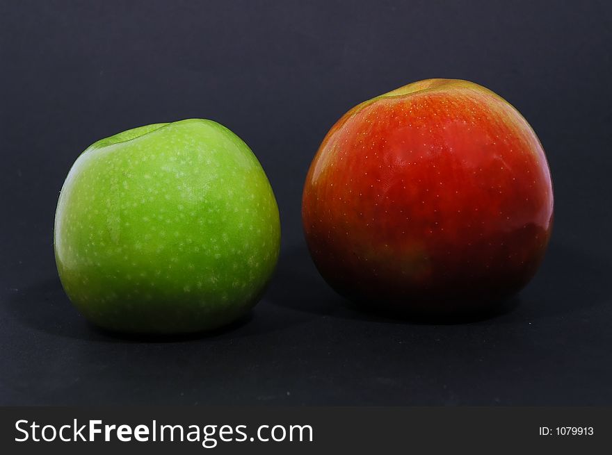 Green and red apple on black background with spotlight