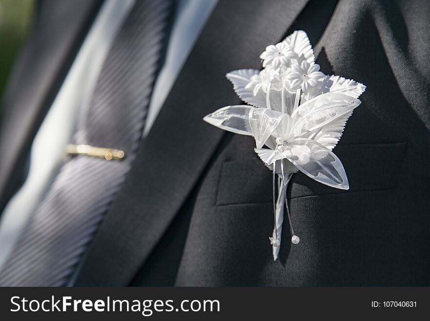 Wedding boutonniere on suit of groom and tie