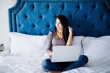 Portrait Of Beautiful Happy Young Woman Lying In Bed And Using Laptop At Home Stock Photo