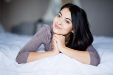 Pure Beauty. Beautiful Young Woman Adjusting Her Hair And Looking At Camera While Lying On The Bed At Home Stock Images