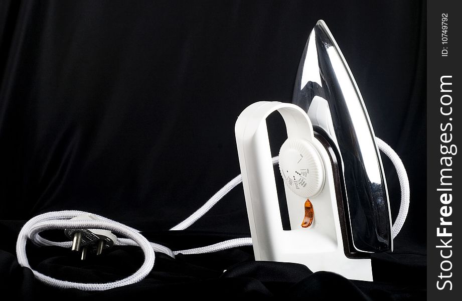 A white Iron on black background showing its cord and power plug. A white Iron on black background showing its cord and power plug.