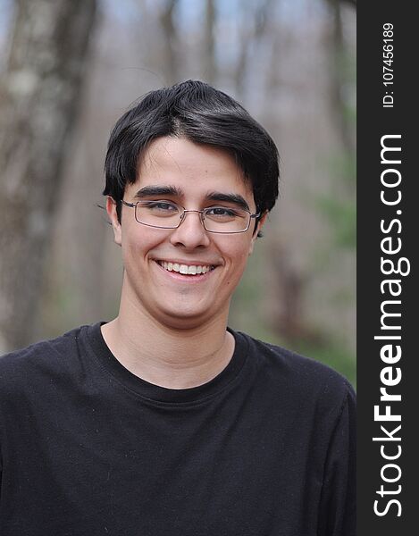 A handsome Latin teen is smiling and looking down with a very happy and sweet expression. A handsome Latin teen is smiling and looking down with a very happy and sweet expression.