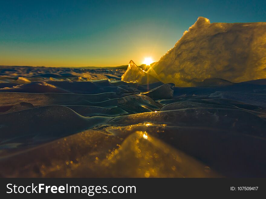 Pure Transparent Ice Of Lake Baikal Through The Sun Is Shining In The Sunset