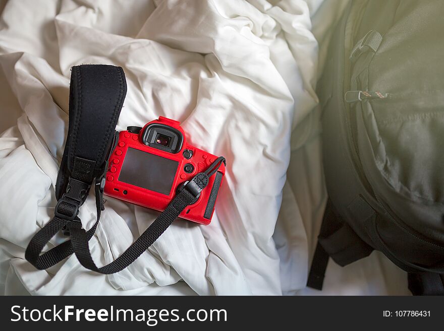 Camera and bag on a bed in the morning.