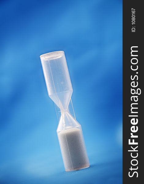 Plastic sand timer against a blue backdrop