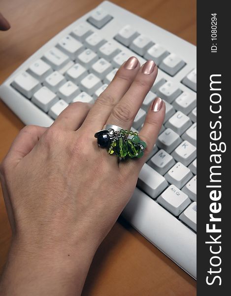 Hand with big ring is typing at the computer keyboard