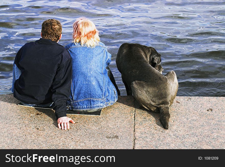 A couple and a dog sitting at the embankment of Neva river in Saint Petersburg. A couple and a dog sitting at the embankment of Neva river in Saint Petersburg.