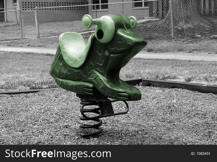 Green frog spring toy in a playground in a neighborhood. Green frog spring toy in a playground in a neighborhood.