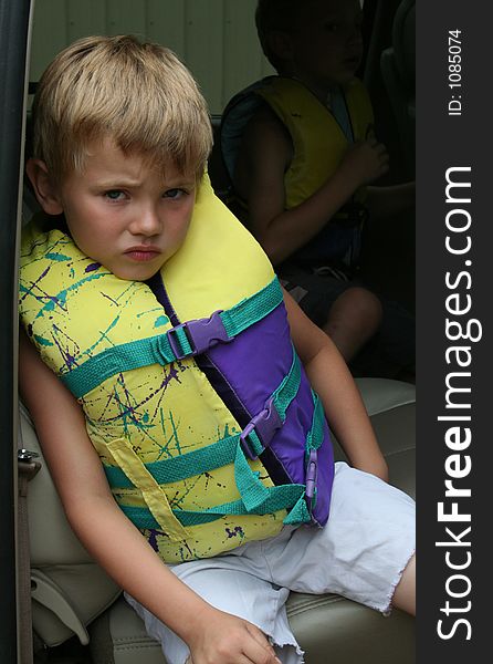 Young boy in a life jacket waiting impatiently in the vehicle to go swimming. Copyspace upper right. Young boy in a life jacket waiting impatiently in the vehicle to go swimming. Copyspace upper right.