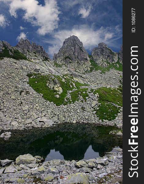 Three razor sharp mountains peak reflecting in the small glacial lake from Retezat Mountains - Romania. Three razor sharp mountains peak reflecting in the small glacial lake from Retezat Mountains - Romania