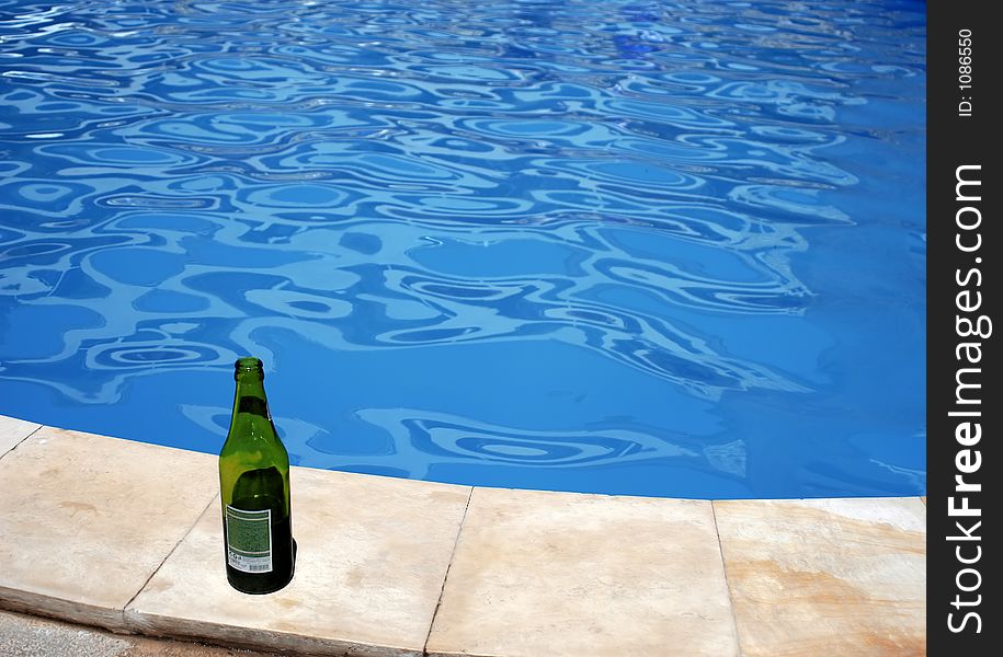 Green empty bottle of beer on the pool border