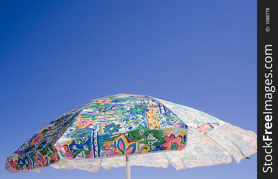 A bright tropical umbrella keeps the sun off at the beach. A bright tropical umbrella keeps the sun off at the beach.