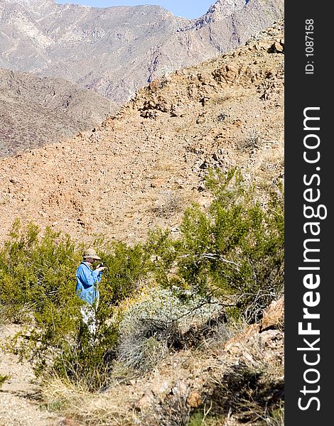 Mature women hiker taking pictures of desert flowers during a long hike in the desert.