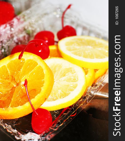 Cherries, lemons, oranges, and strawberries in a plastic container. Cherries, lemons, oranges, and strawberries in a plastic container
