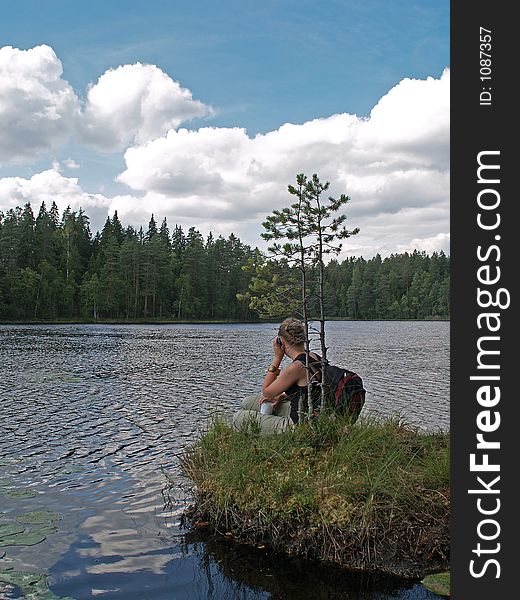 Young girl chats with mobile phone on a shore of lake