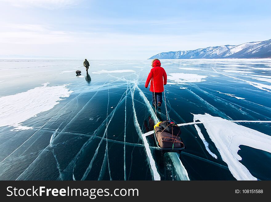 Woman with a sledge walk is on the ice of Lake Baikal