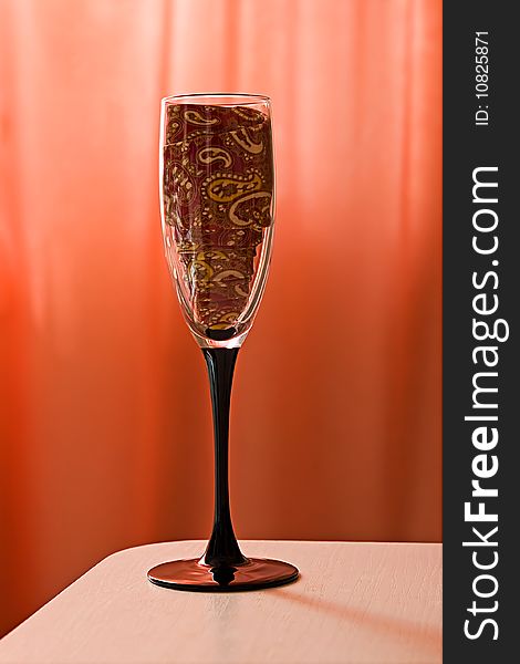 Empty champagne glass with a stylish red tie inside. Empty champagne glass with a stylish red tie inside