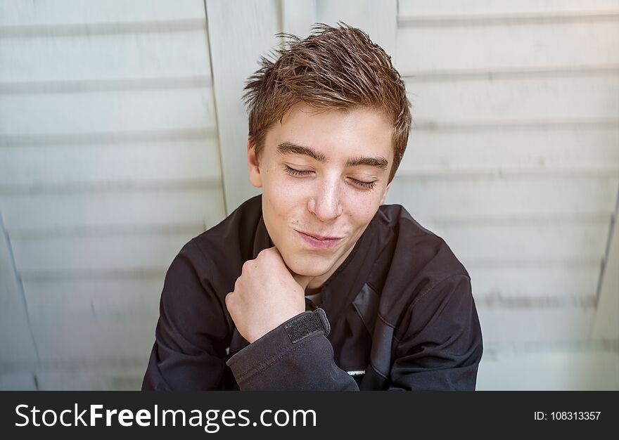 Portrait of a smiling young man sitting in front of a door