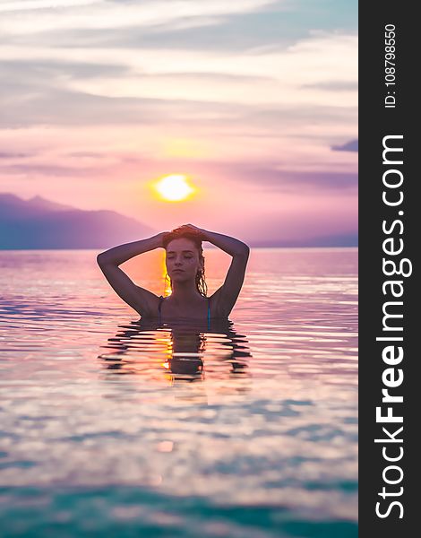 Selective Focus Photo Of A Woman Bathing In Body Of Water During Golden Hour