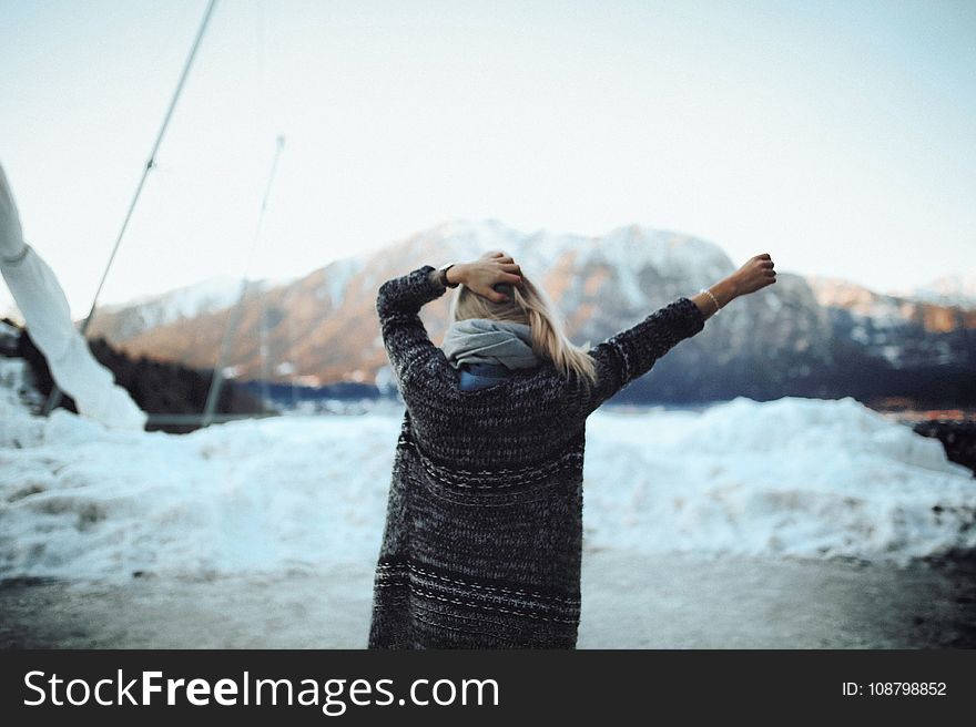 Woman in Gray and Black Tribal Cardigan Standing in Front of Snow Fields