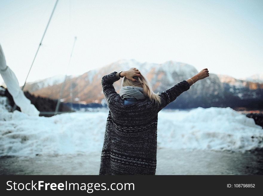 Woman In Gray And Black Tribal Cardigan Standing In Front Of Snow Fields