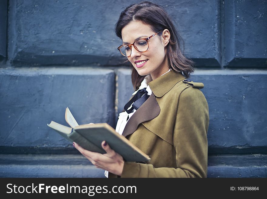 Woman In Brown Suede Peacoat Reading A Book