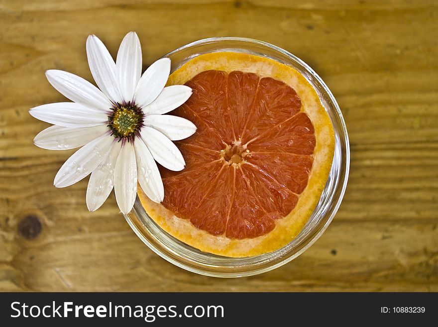 A cut grapefruit with a large daisy. A cut grapefruit with a large daisy