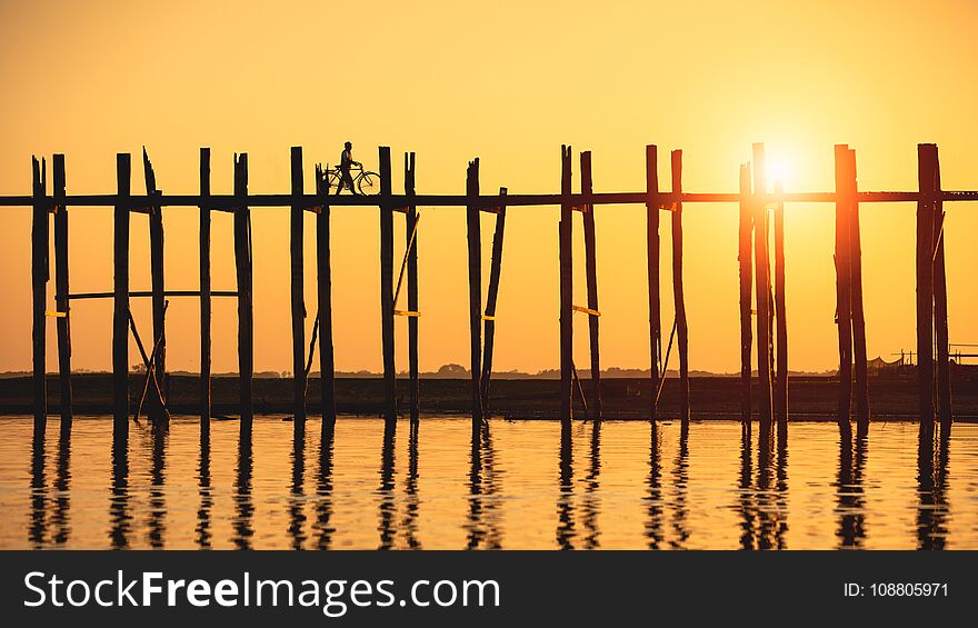 Silhouette of people traveling across the U Bein Bridge in the evening. Mandalay Myanmar