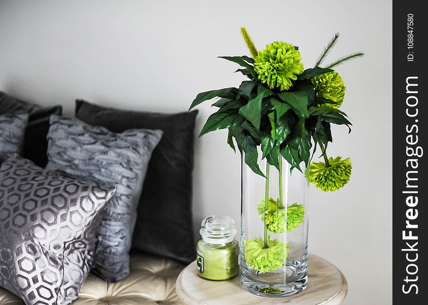 Clear Glass Vase With Green Flowers On Brown Wooden End Table