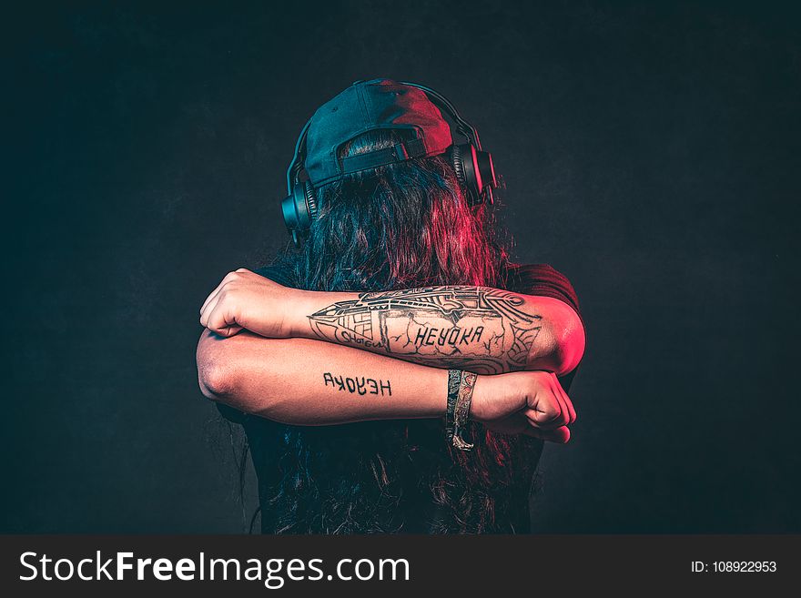 Man In Black Top Wearing Headphones Showing His Tattoos