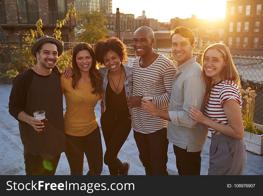 Friends at a rooftop party in Brooklyn smiling to camera